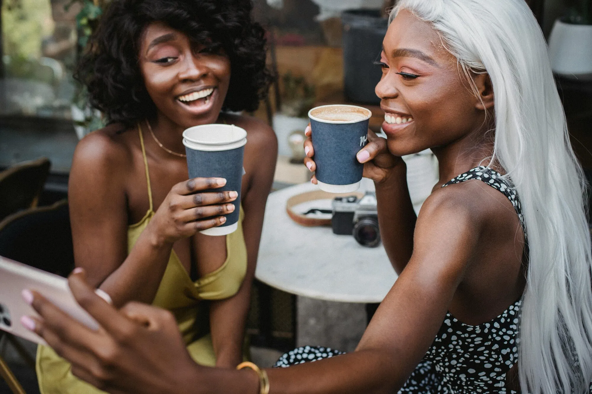 Deux amies en terrasse de café, un téléphone à la main