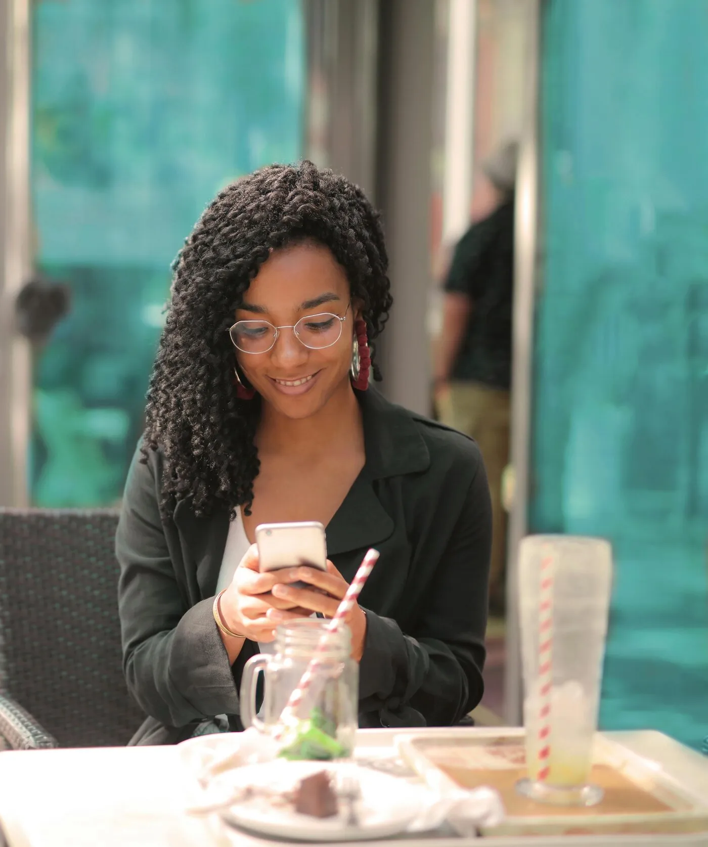 Cliente consultant le menu sur son téléphone à la terrasse d’un café